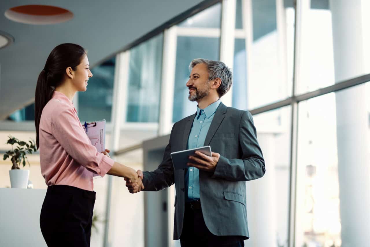 two employees shaking hands and talking about benefits and perks employment contracts
