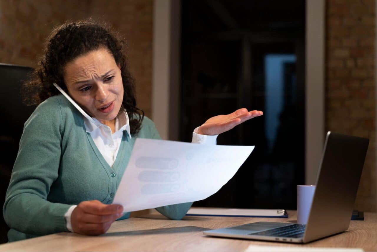 A person on the phone scrutinises a contract.