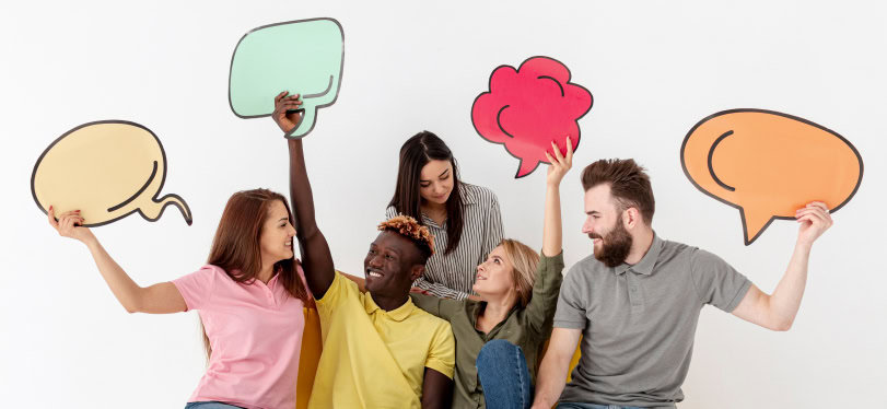 A startup gang huddle. They are holding aloft cartoon speech bubbles to represent communication.